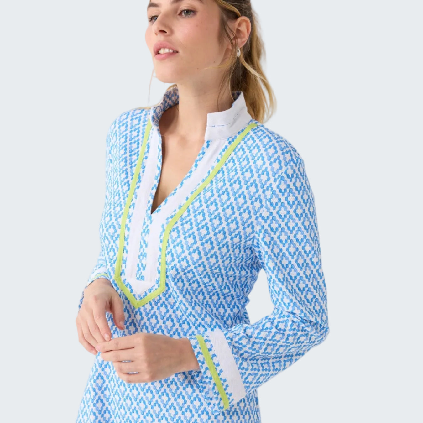 Woman wearing a blue and white patterned dress with green trim on a white background