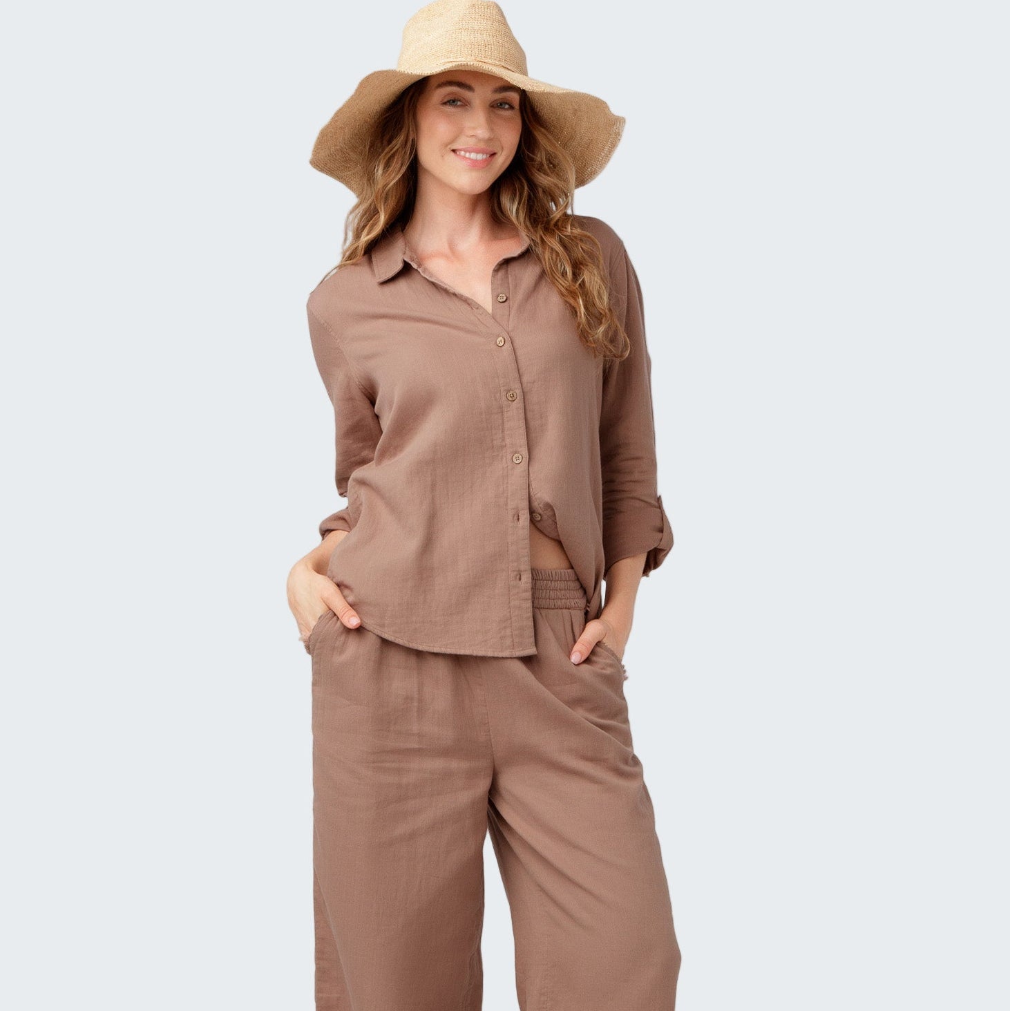 Woman wearing a brown outfit with a wide-brimmed hat on a white background