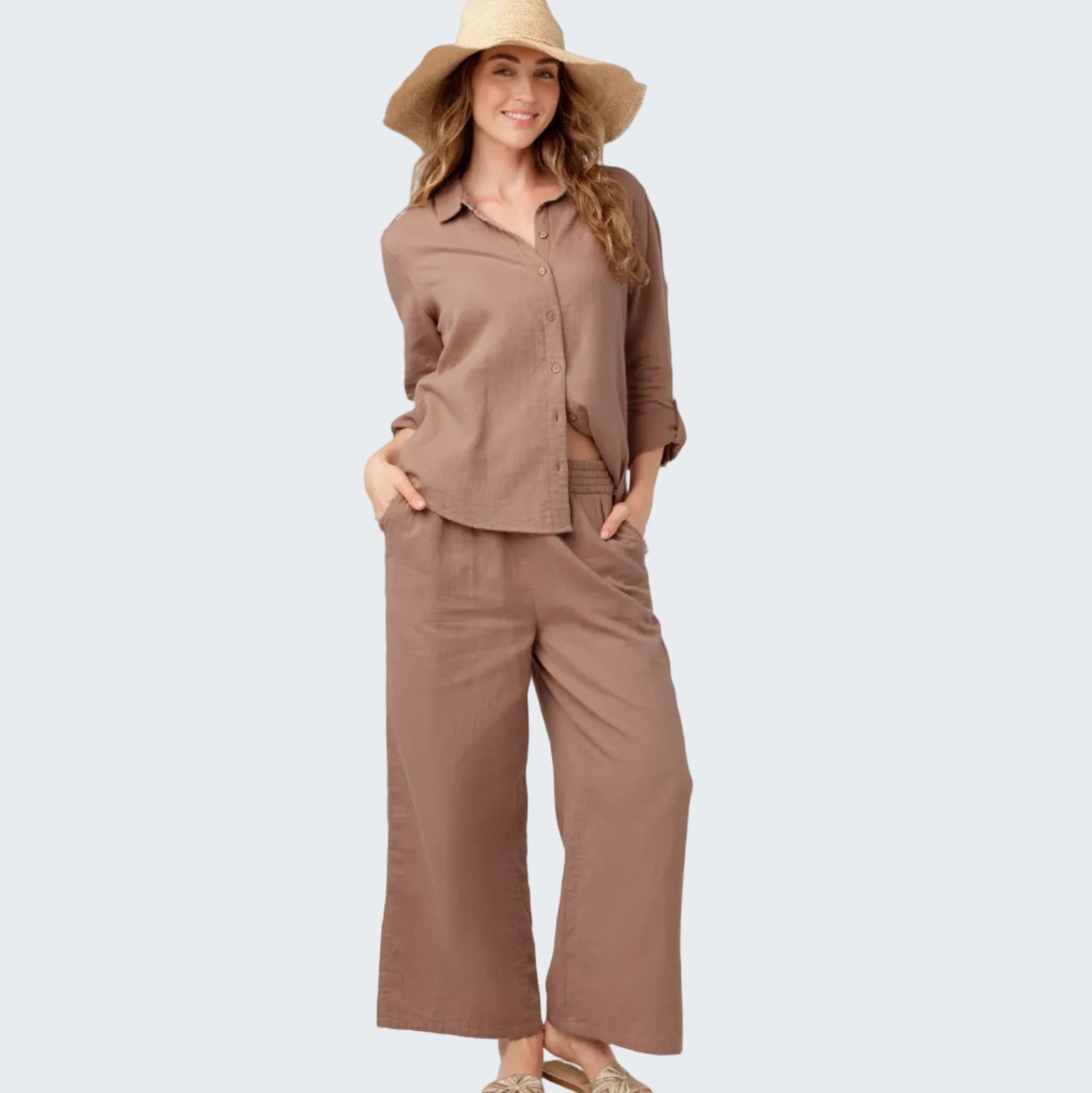Woman wearing a brown outfit with a wide-brimmed hat on a white background