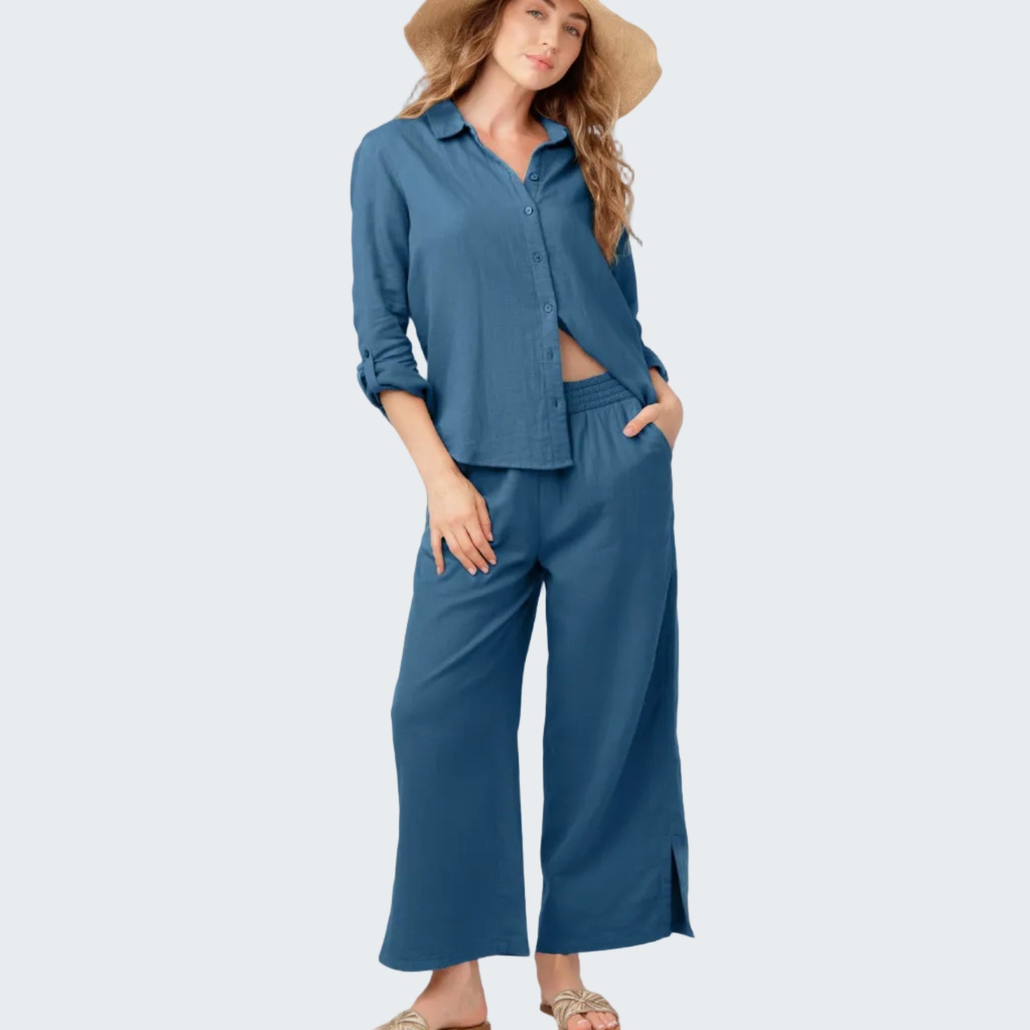 Woman wearing a blue outfit with wide-leg pants and a hat on a white background