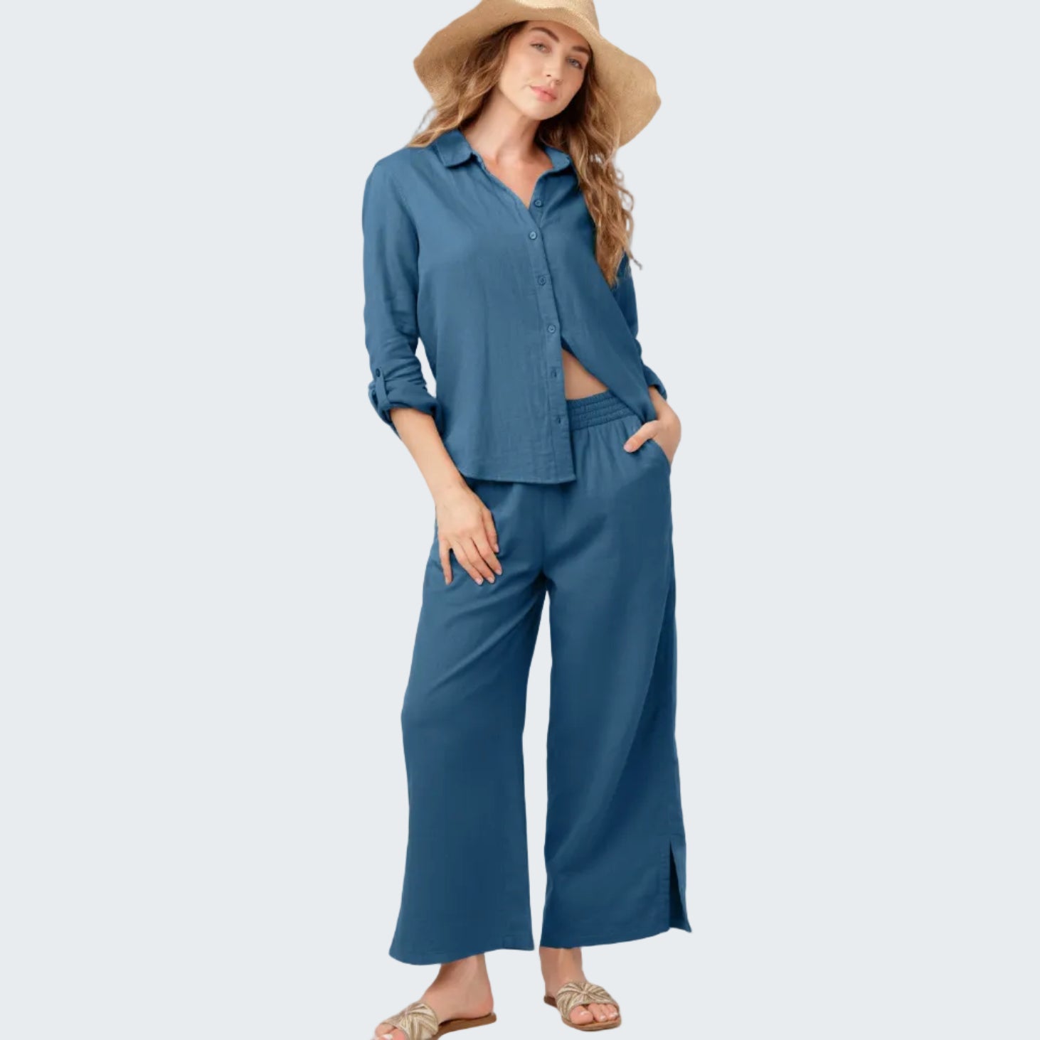 Woman wearing a blue outfit with wide-leg pants and a hat on a white background