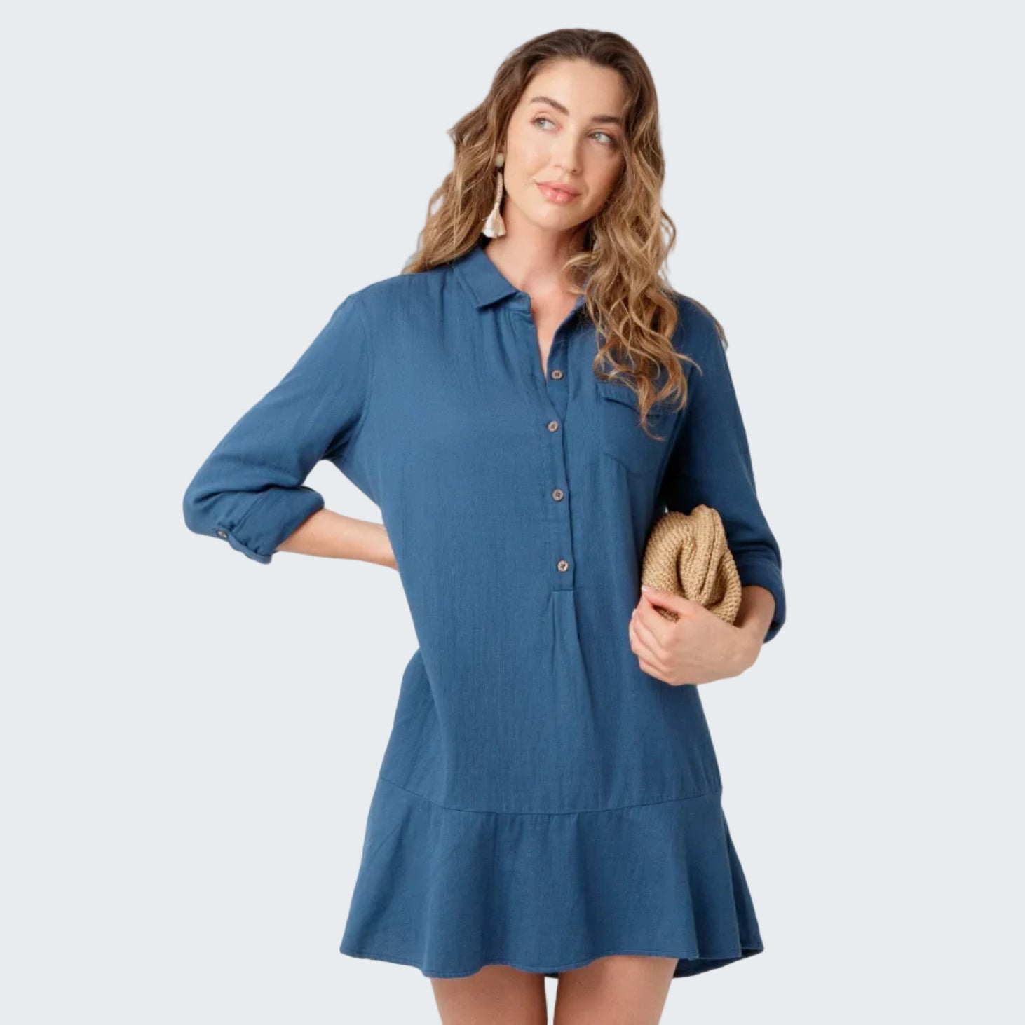 Woman wearing a blue dress holding a clutch against a white background