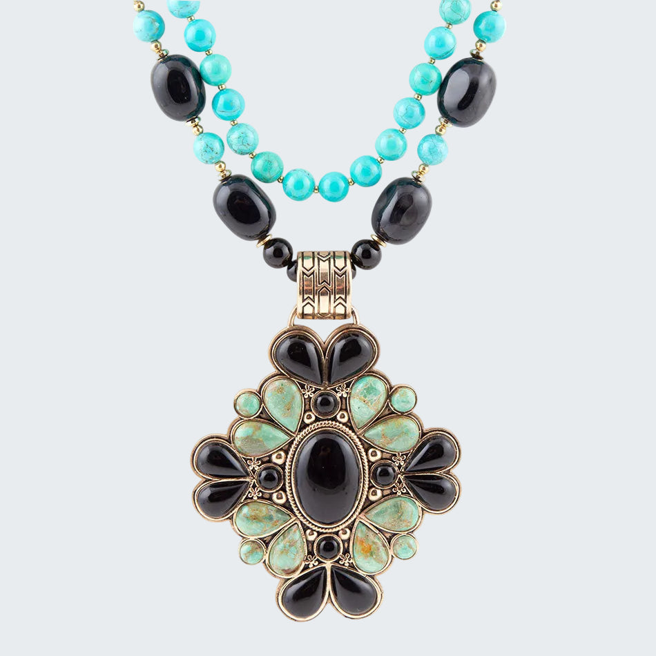 Necklace with turquoise and black beads and a decorative pendant on a white background