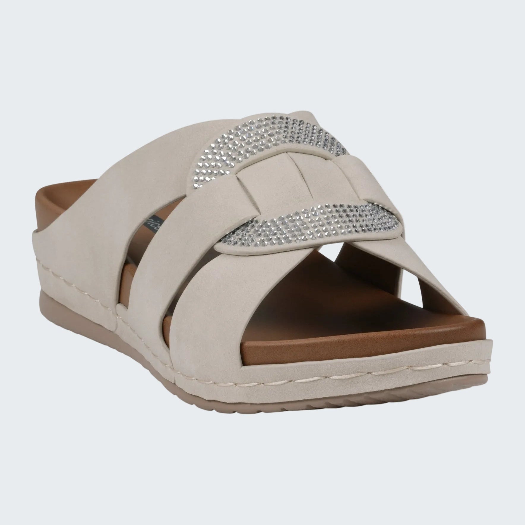 Beige sandal with a brown sole and silver embellishments on a white background