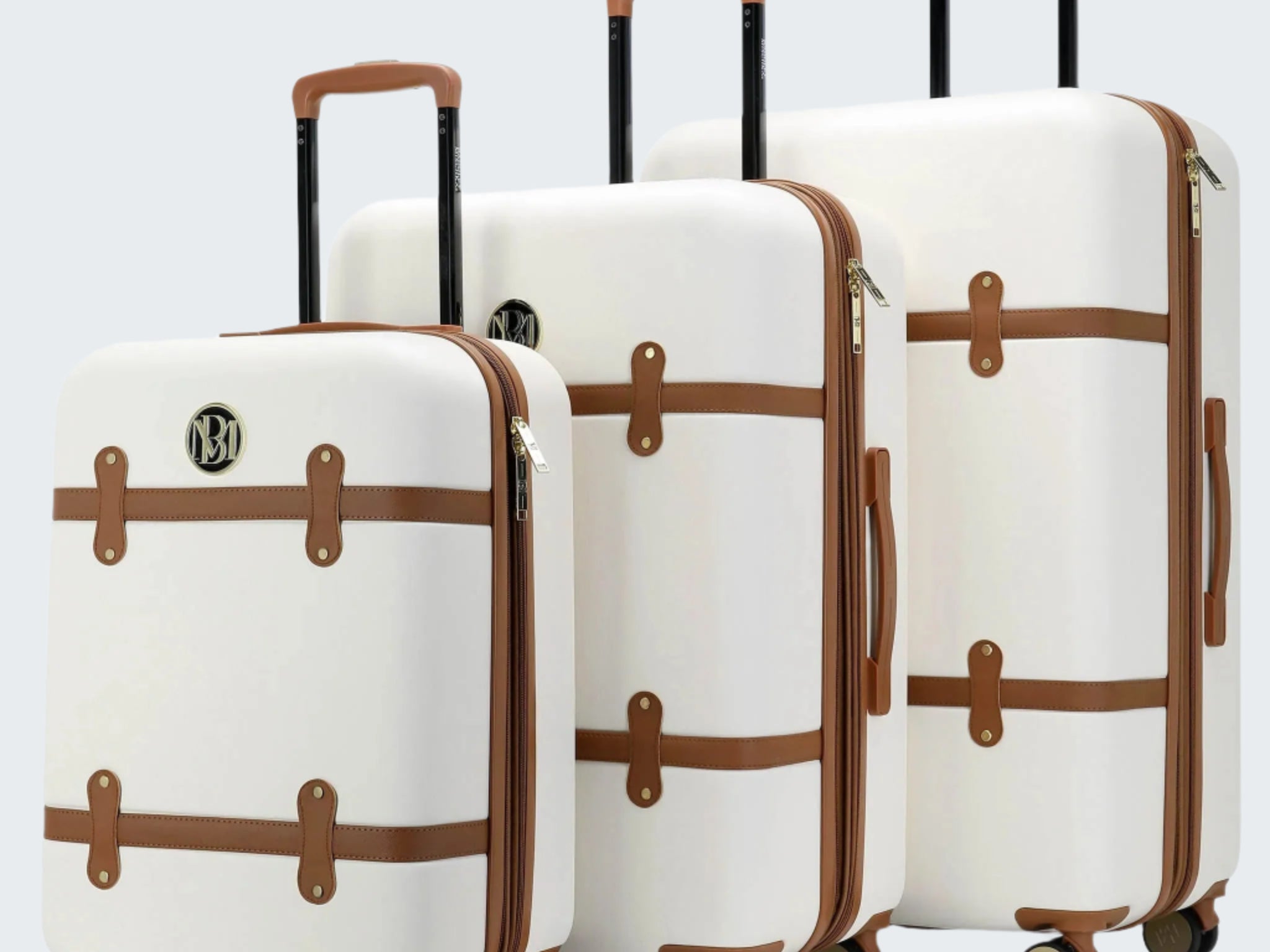 Set of three white suitcases with brown accents on a white background