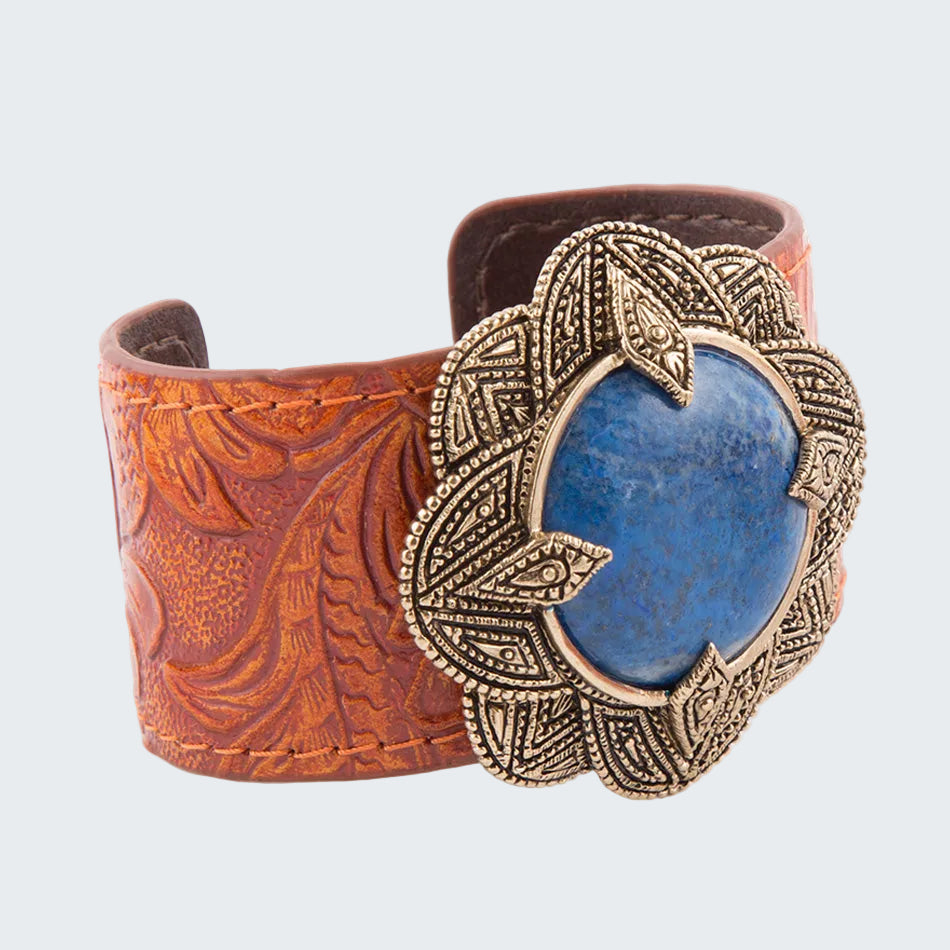 Brown leather cuff with decorative metal and blue stone on a white background
