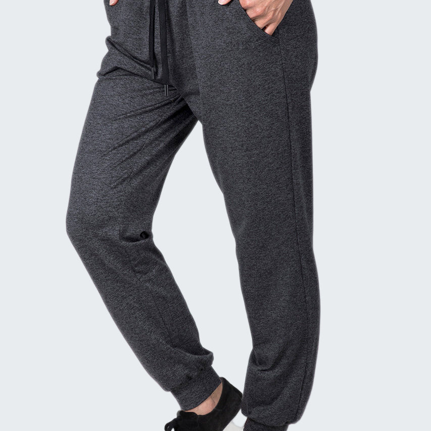 Person wearing gray jogger pants and black sneakers on a white background