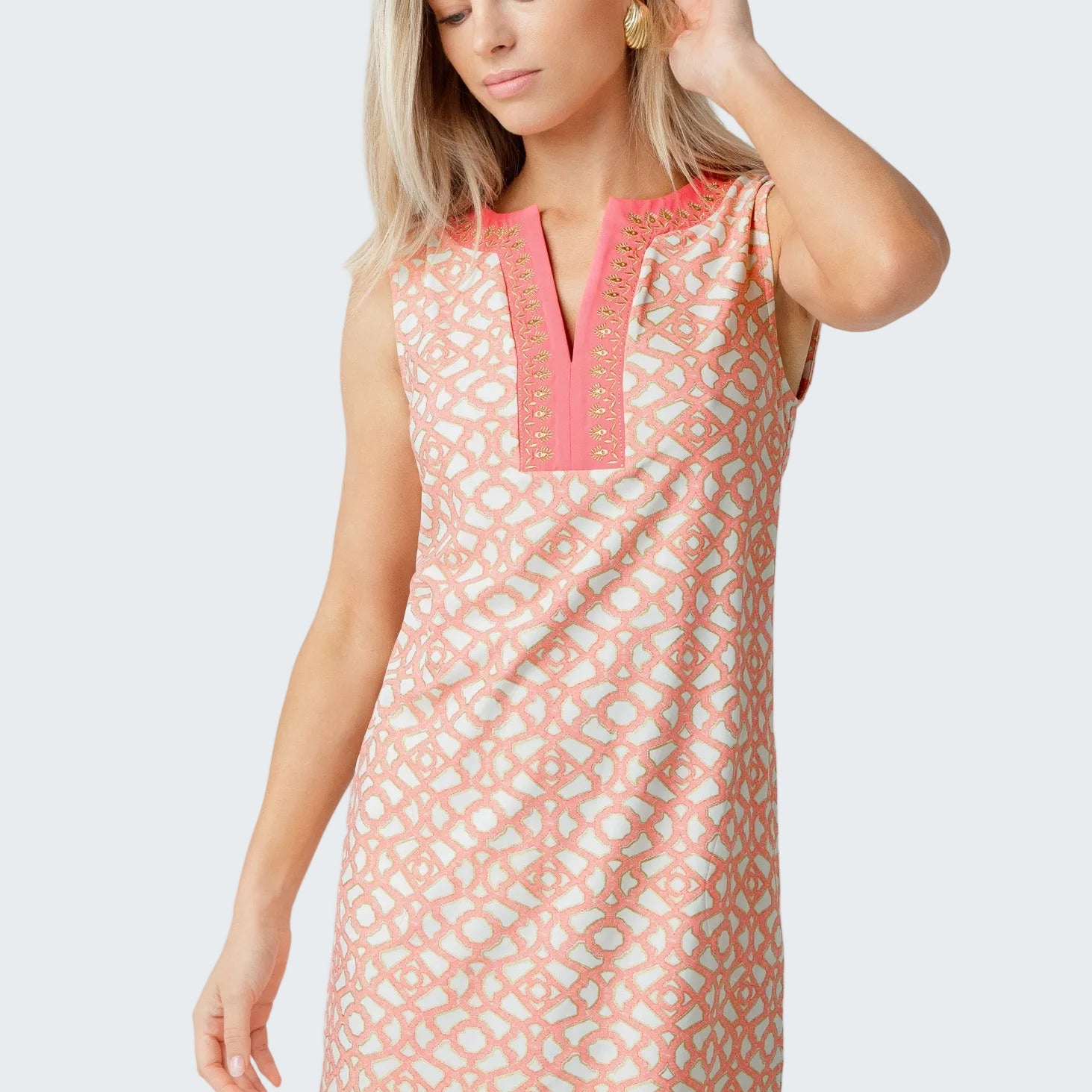 Woman wearing a sleeveless dress with pink geometric pattern on a white background