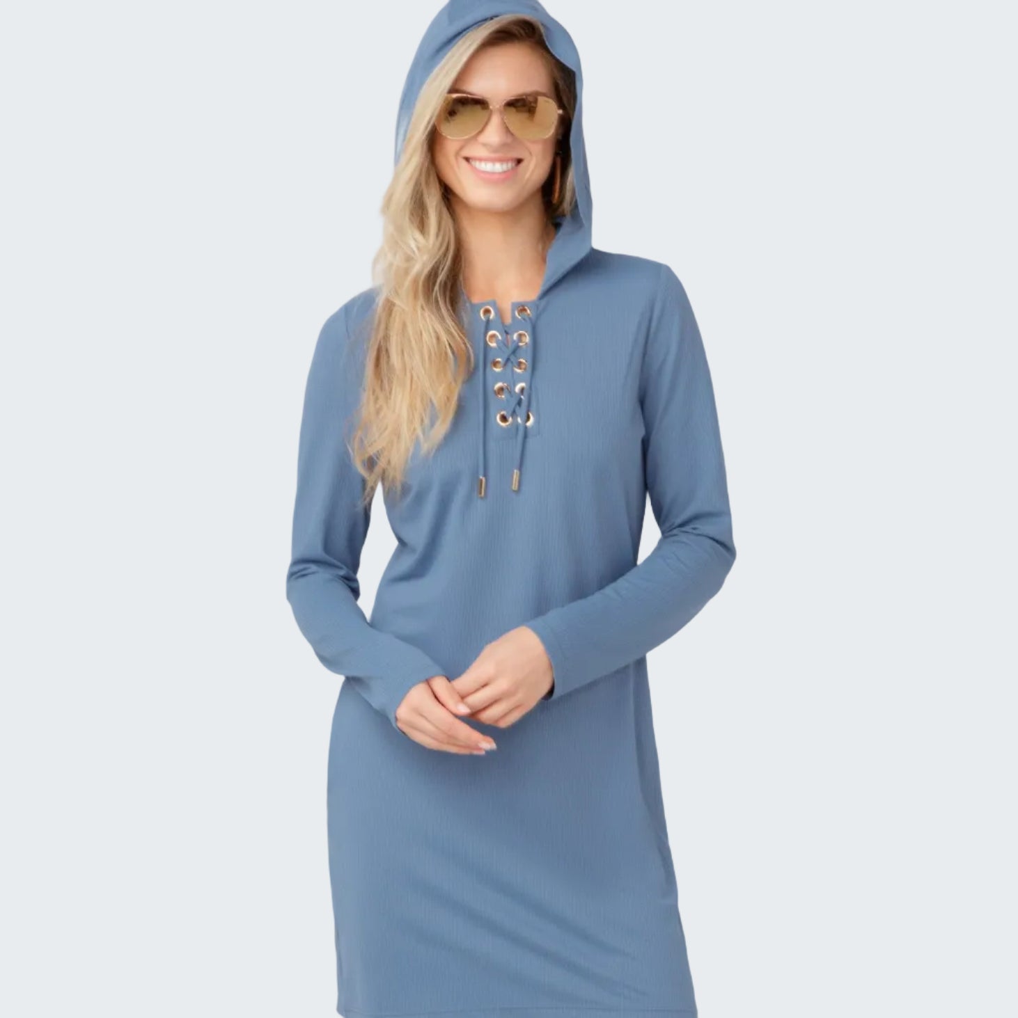 Woman wearing a blue hooded dress with lace-up details on a light gray background