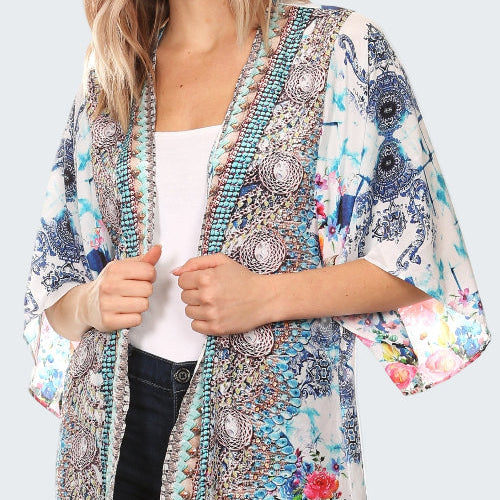 Woman wearing a colorful kimono-style jacket with floral and abstract patterns on a white background