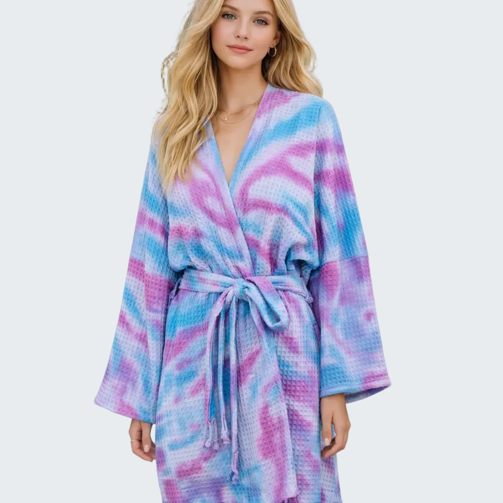 Woman wearing a colorful tie-dye robe by a poolside.