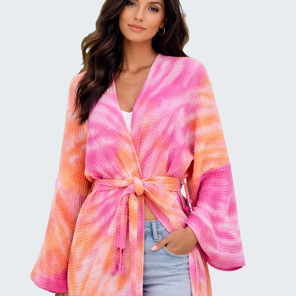 Woman wearing a pink and orange tie-dye kimono by a poolside.