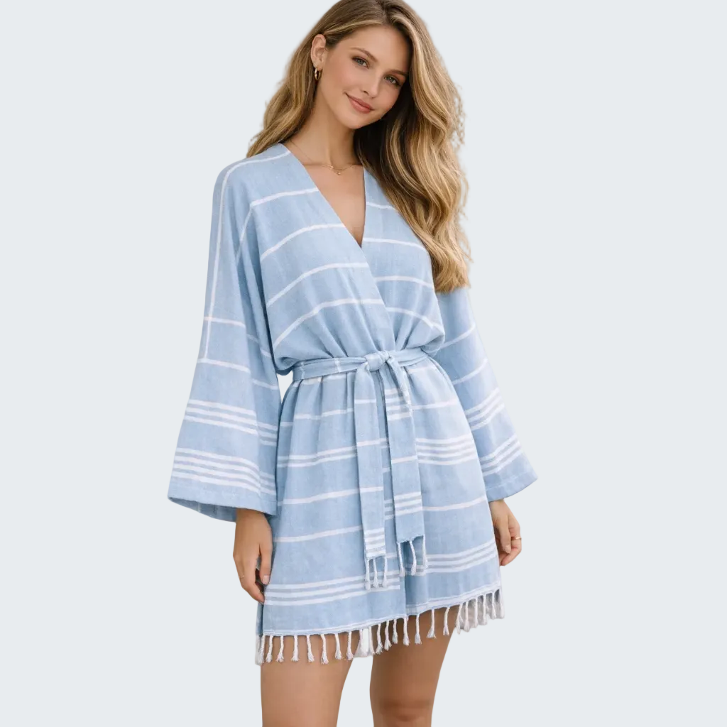 Woman wearing a blue striped dress with fringe details outdoors.