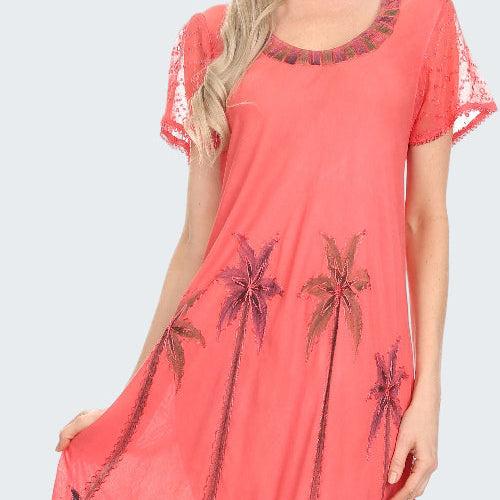 Coral dress with palm tree pattern worn by a model on a white background