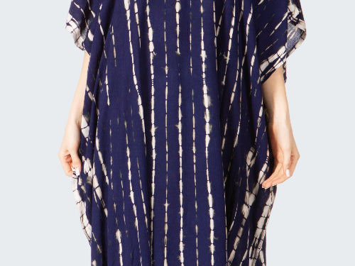 Woman wearing a navy blue tie-dye dress on a white background