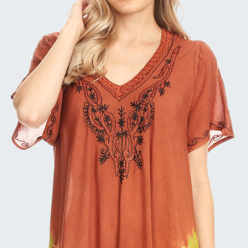 Woman wearing a rust and yellow dress with floral embroidery