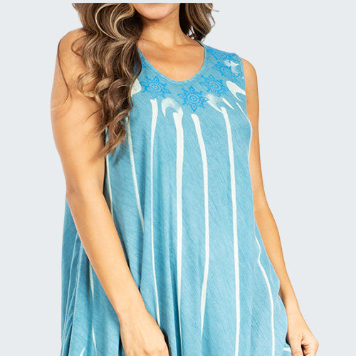 Woman wearing a blue sleeveless dress with white patterns on a white background