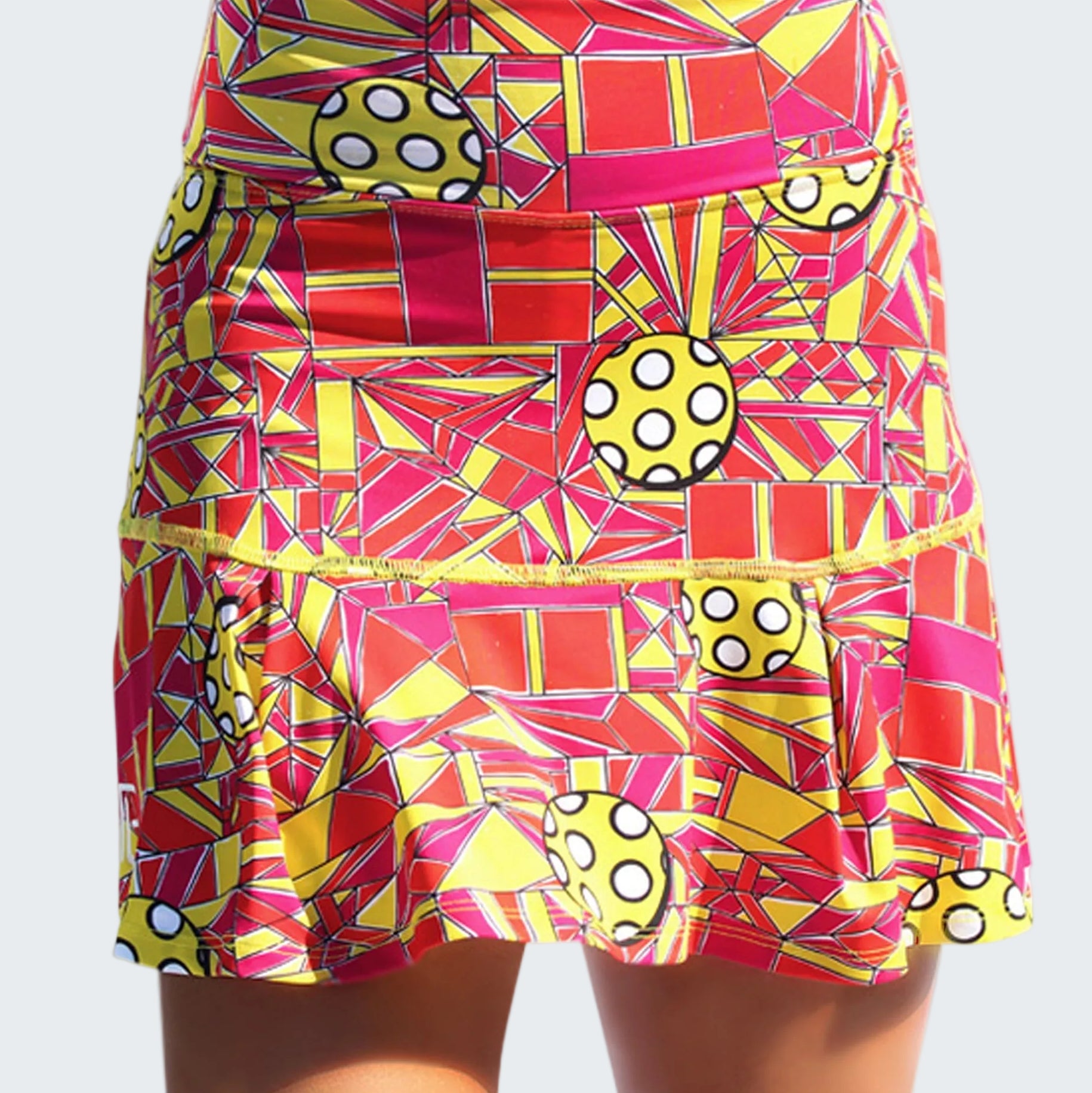 Colorful geometric patterned skirt with polka dot accents on a white background