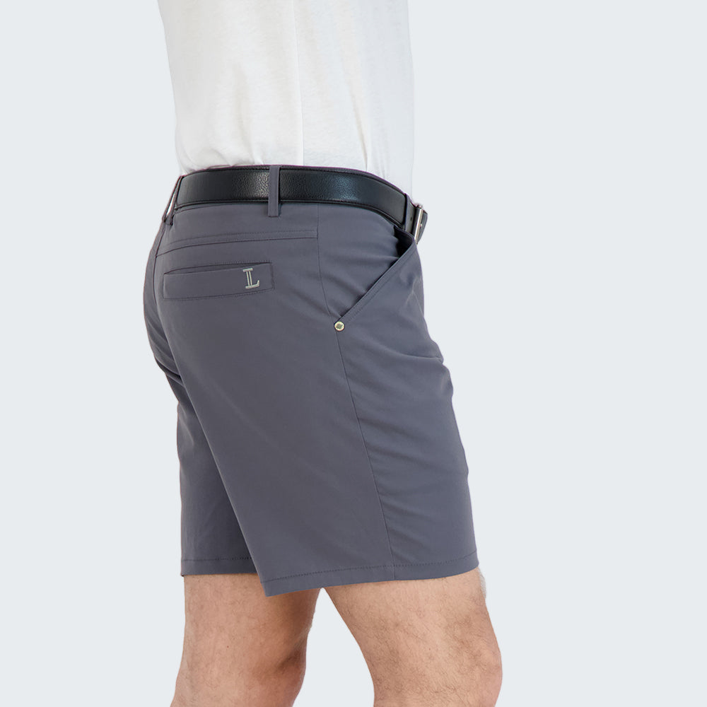 Person wearing gray shorts and black sneakers on a white background