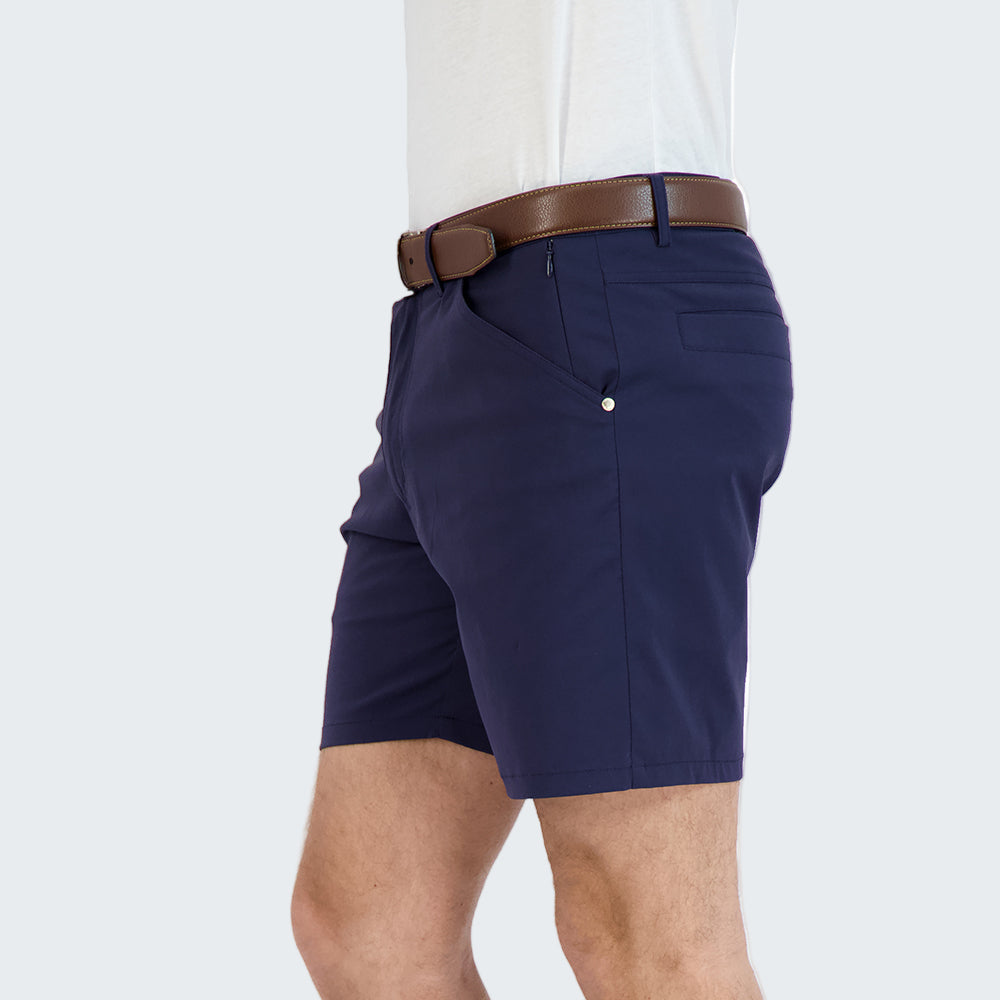 Person wearing navy shorts and black Converse shoes on a white background