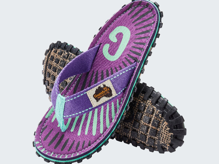 Purple and black sandals with a visible brand logo on a white background