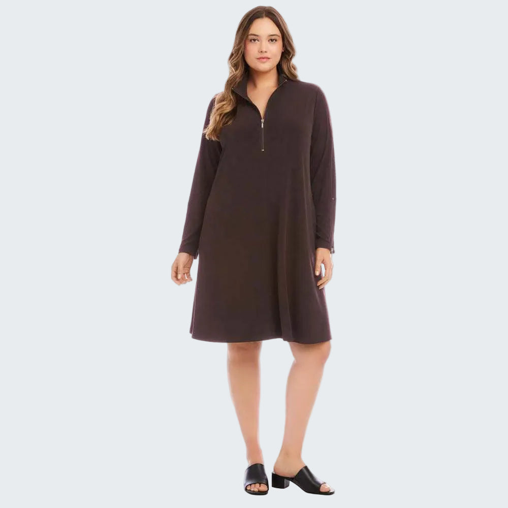 A woman modeling a dark brown long-sleeve quarter-zip dress with a relaxed, A-line silhouette, paired with black slide sandals, against a solid white studio background.