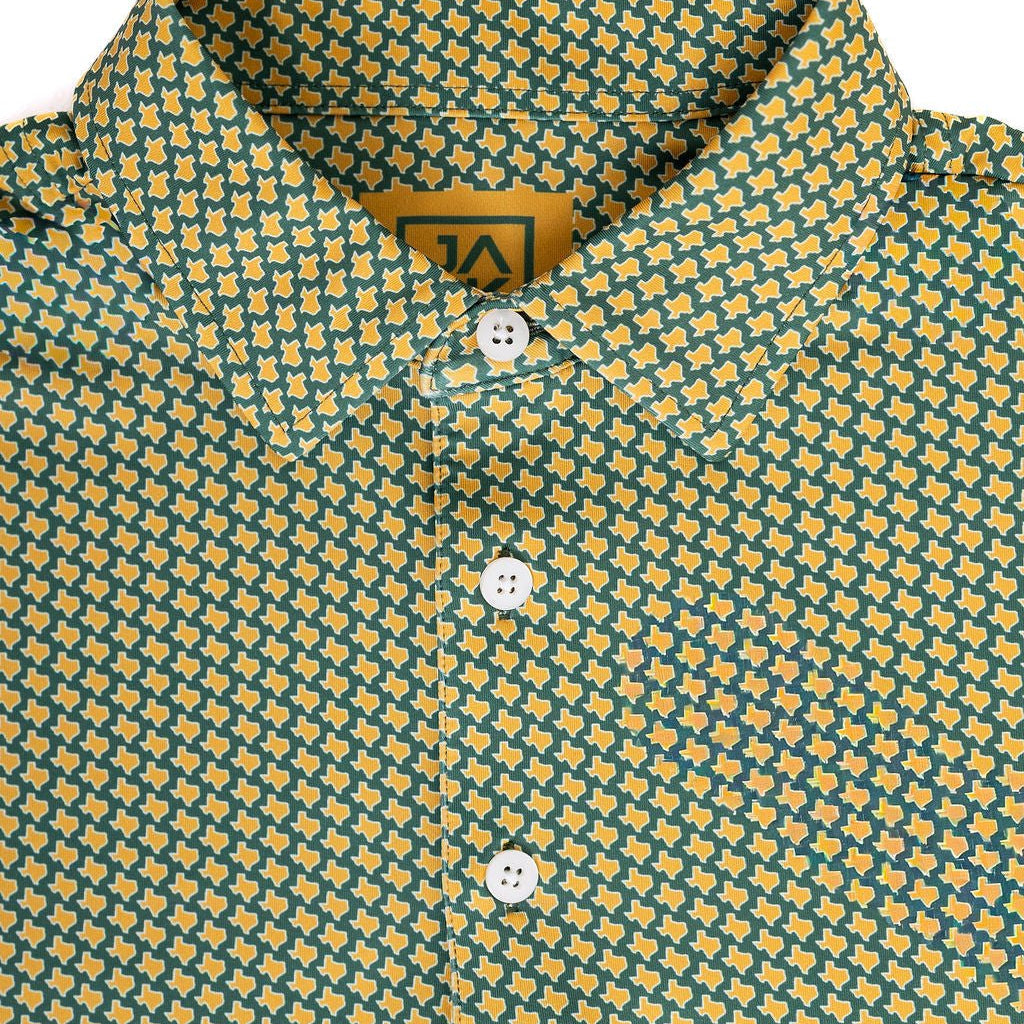 Close-up of a collared button-front shirt with a repeating yellow and teal geometric pattern, white buttons, and a visible neck label.