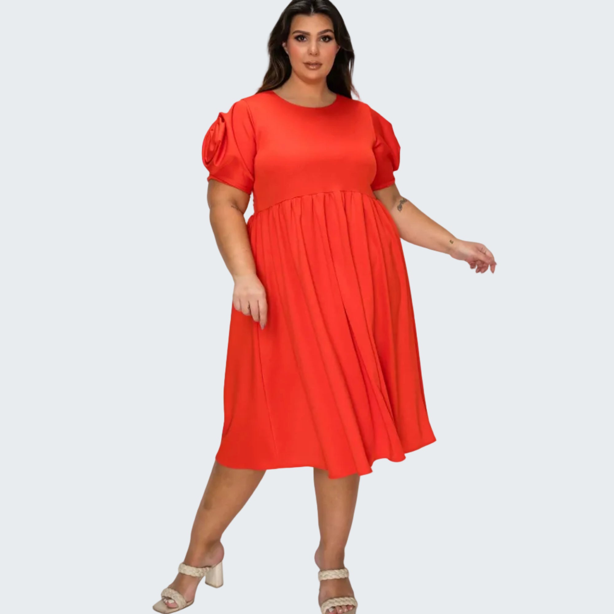 A woman modeling a bright red midi dress with short puff sleeves and a gathered waist, paired with beige heeled sandals, against a plain white background.