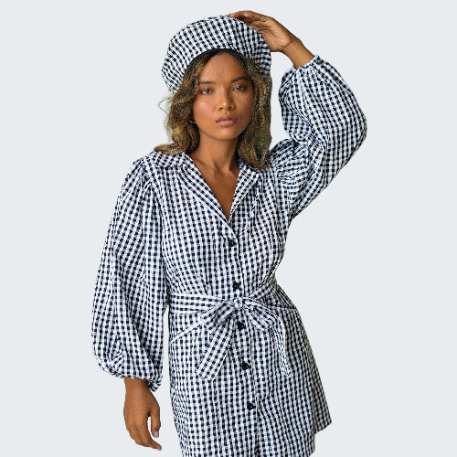 Woman wearing a black and white checkered dress and hat against a plain background