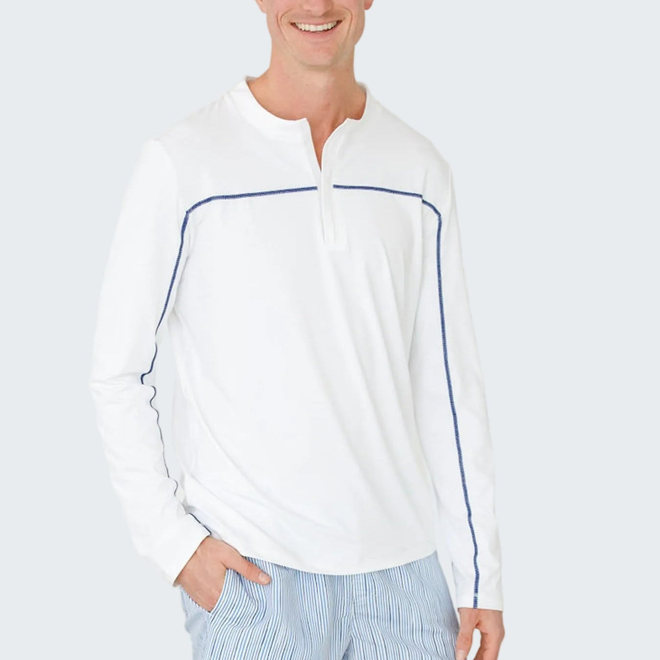 Man wearing a white long-sleeve shirt with blue accents and light blue shorts on a white background