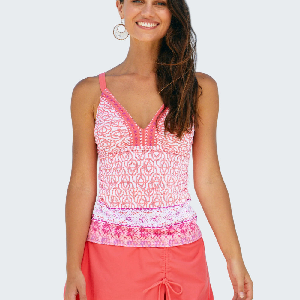 Woman wearing a pink patterned top and coral skirt on a beach