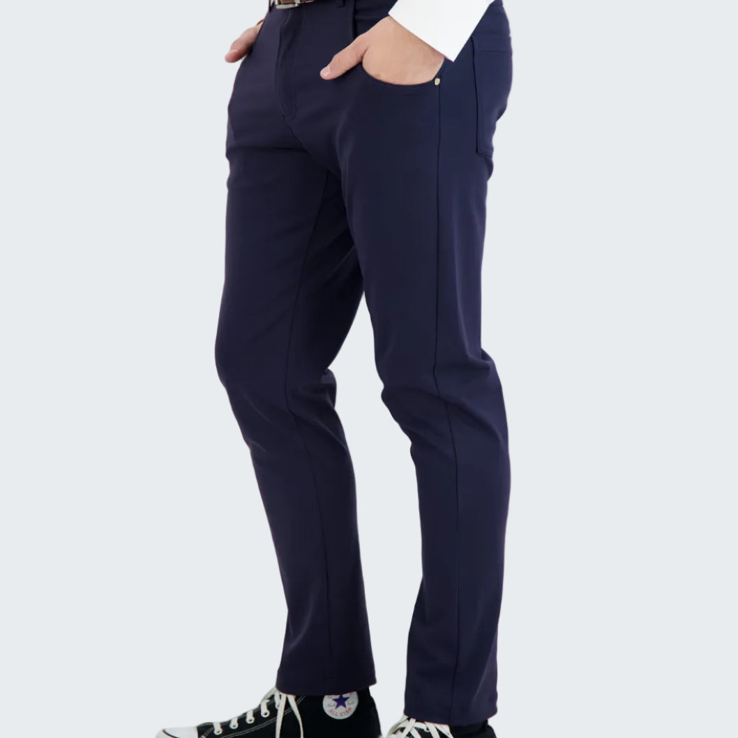 Person wearing navy pants with a white shirt and black sneakers on a white background