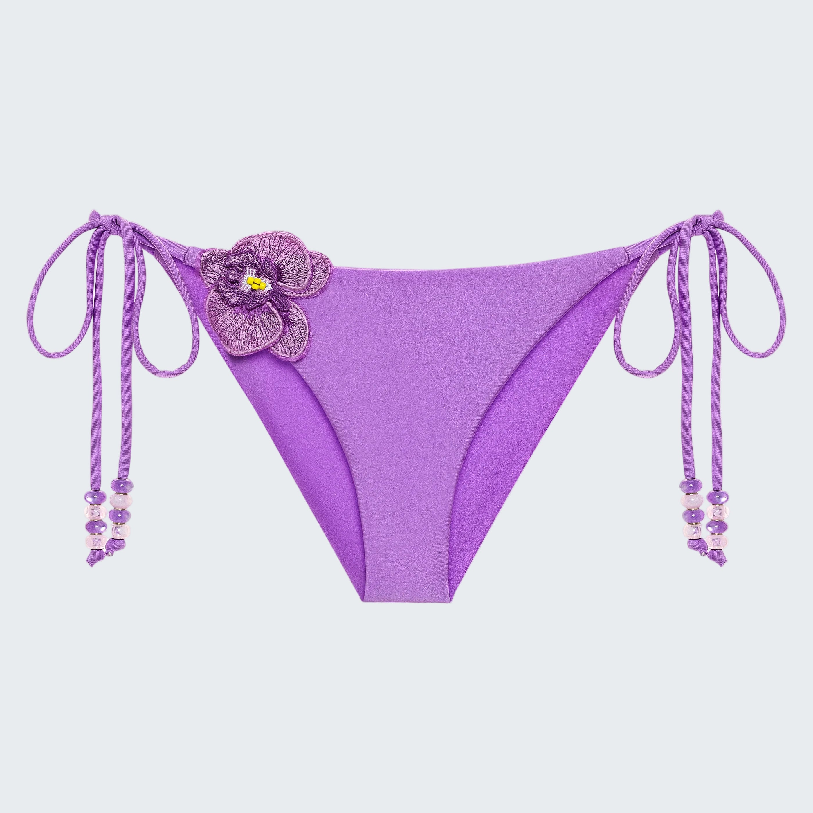 Purple bikini bottom with floral design and string details on a white background