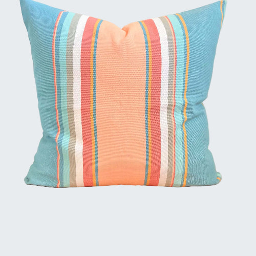 Striped pillow with blue, orange, and white colors on a wooden stool.