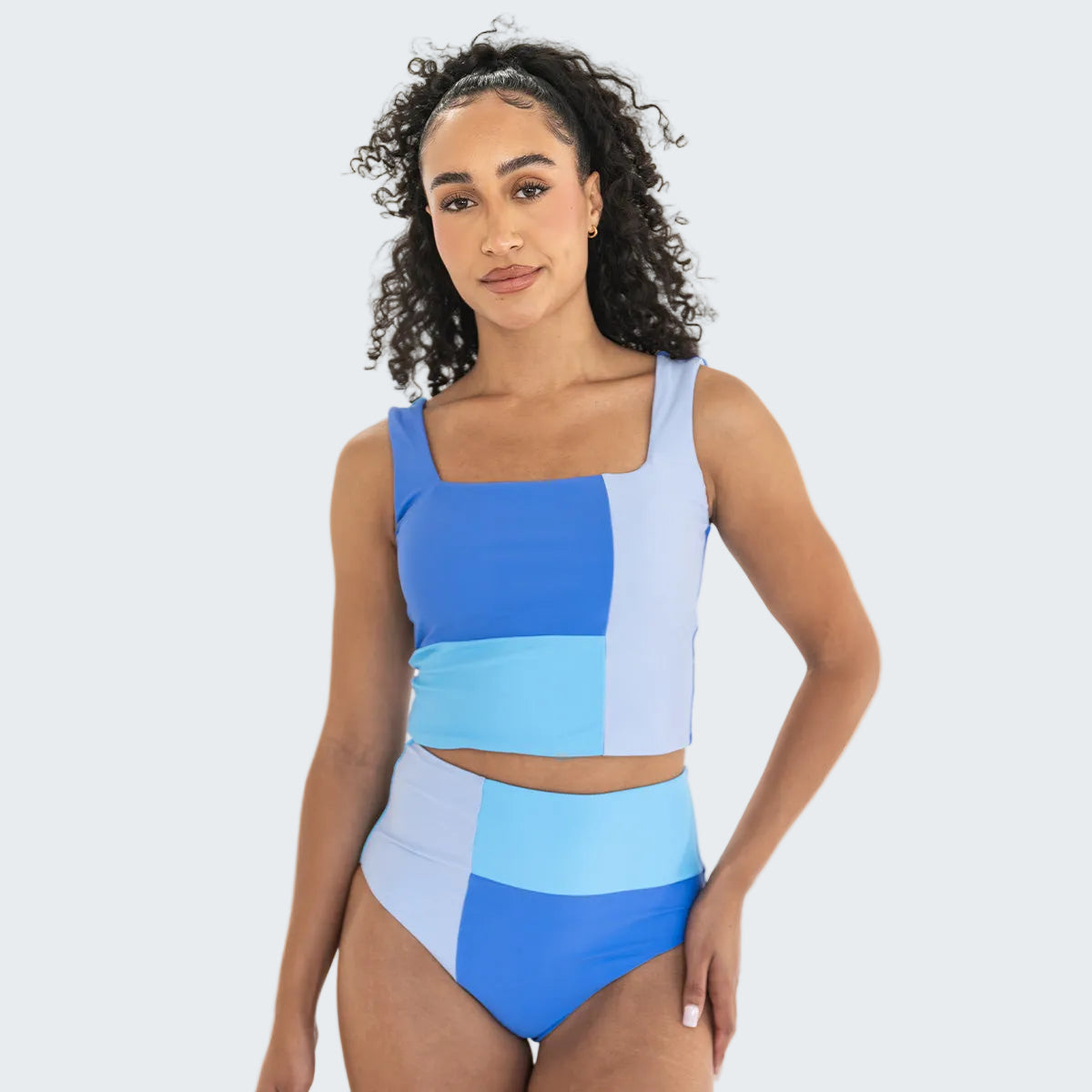 Woman wearing a blue and light blue geometric patterned swimsuit on a white background