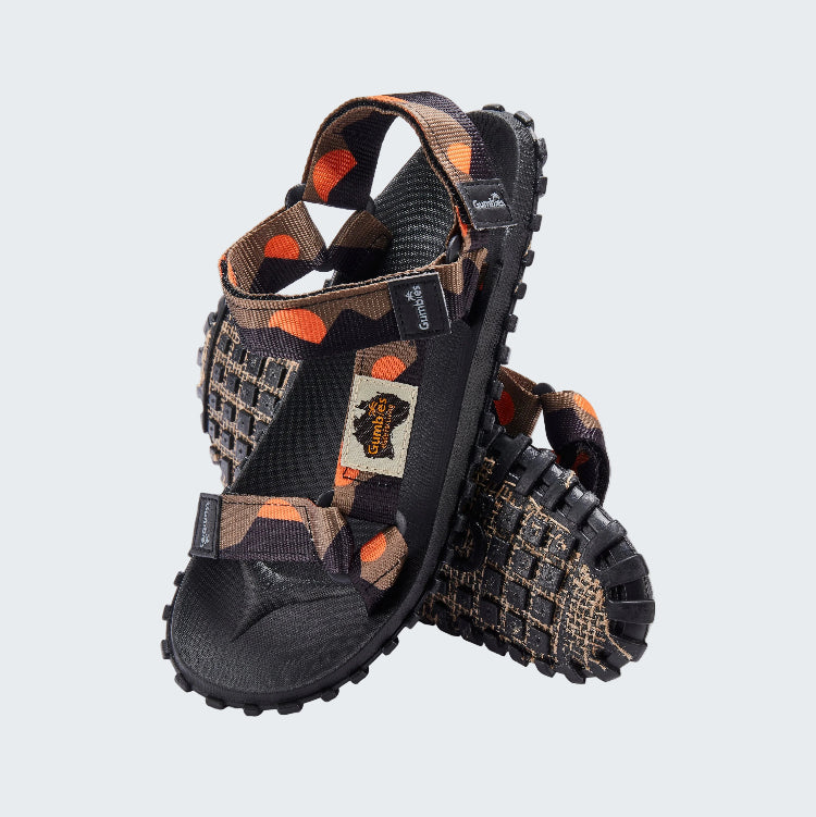 Pair of black and brown sandals with orange accents on a white background