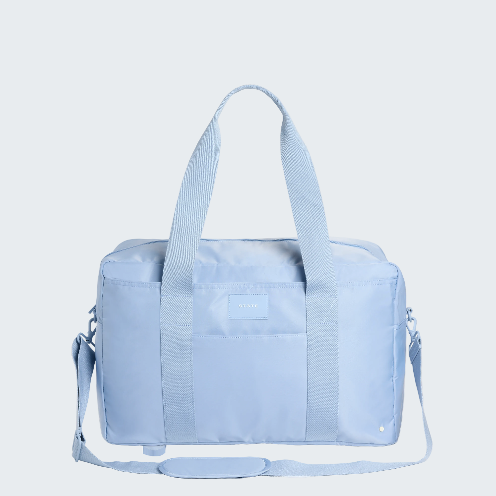Light blue duffel bag with a visible brand logo on a white background