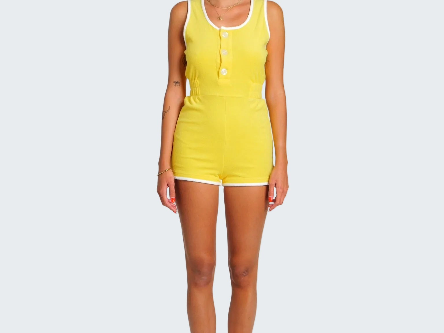 Woman wearing a yellow sleeveless jumpsuit on a white background