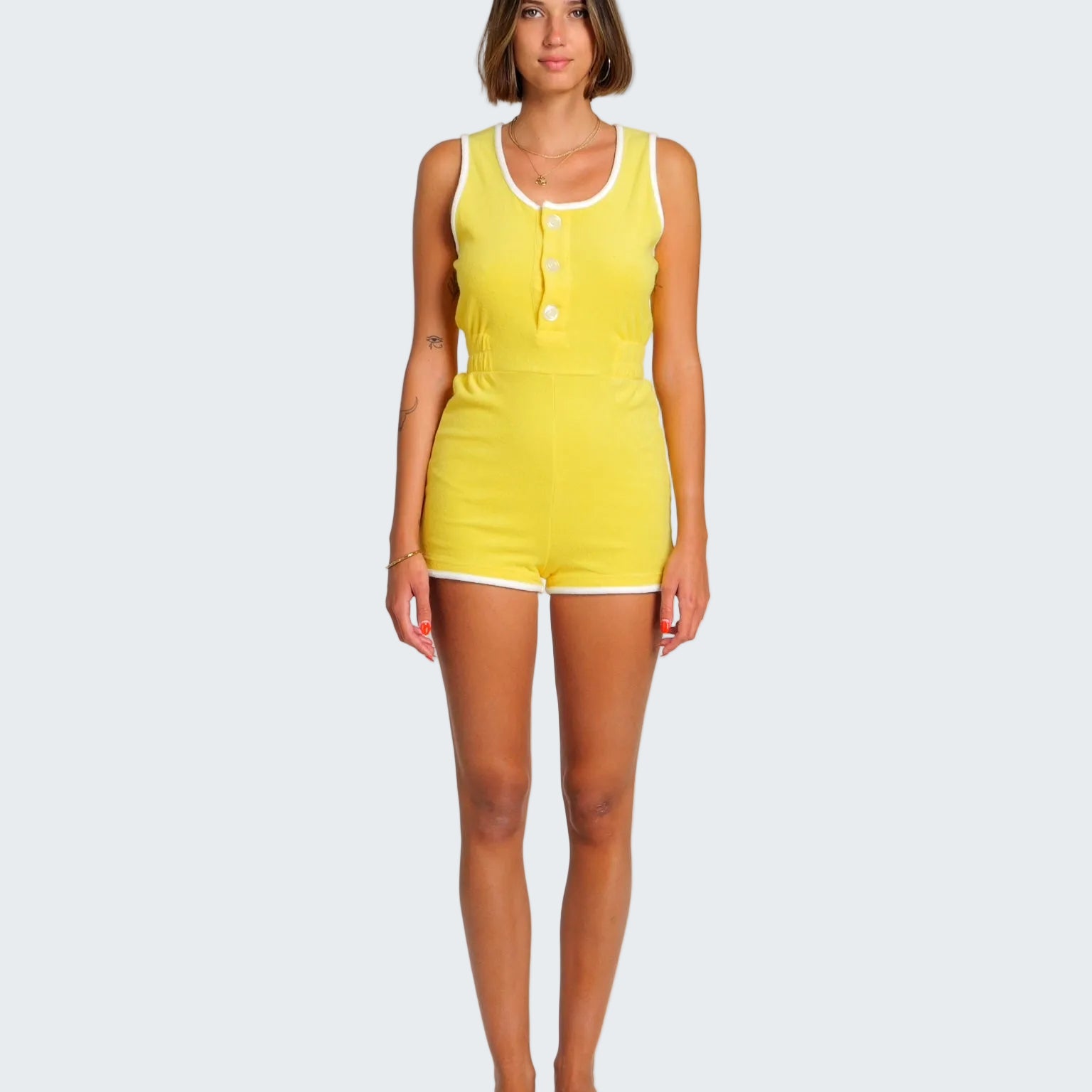 Woman wearing a yellow sleeveless jumpsuit on a white background