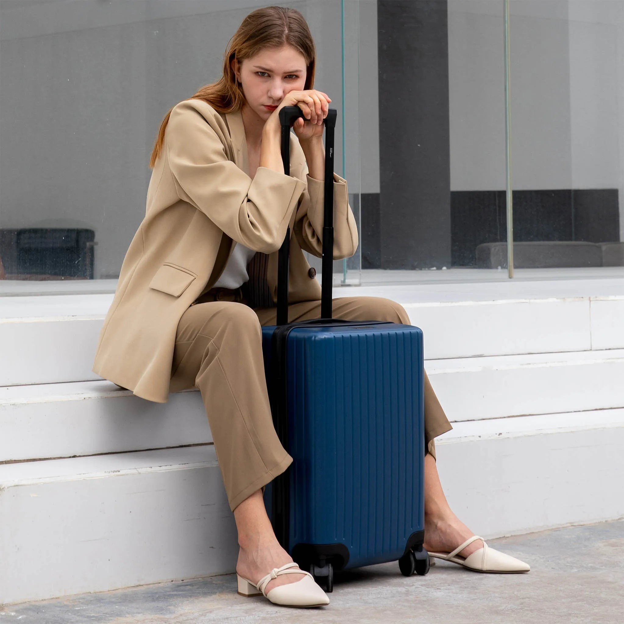 Woman sitting on steps with a blue suitcase