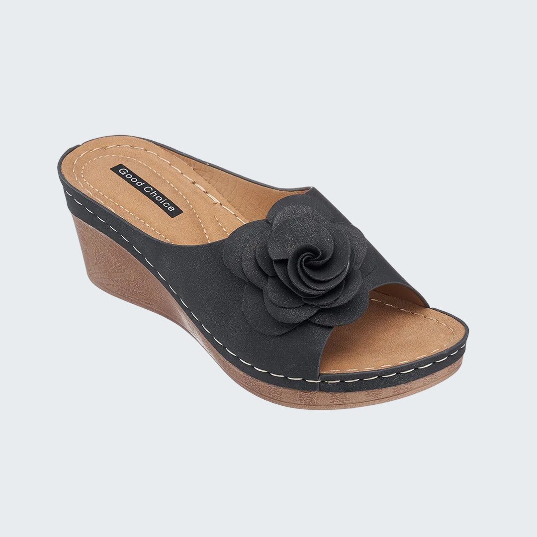 Black wedge sandal with a flower detail on a white background