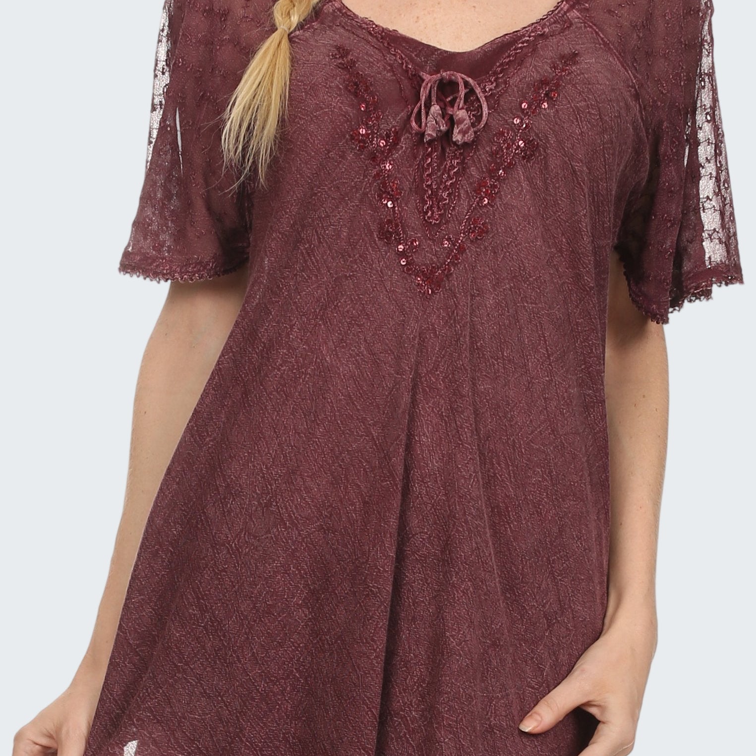 Woman wearing a burgundy lace top with embellishments on a white background