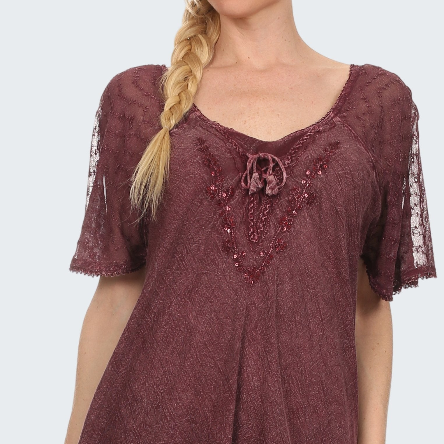 Woman wearing a burgundy lace top with embellishments on a white background