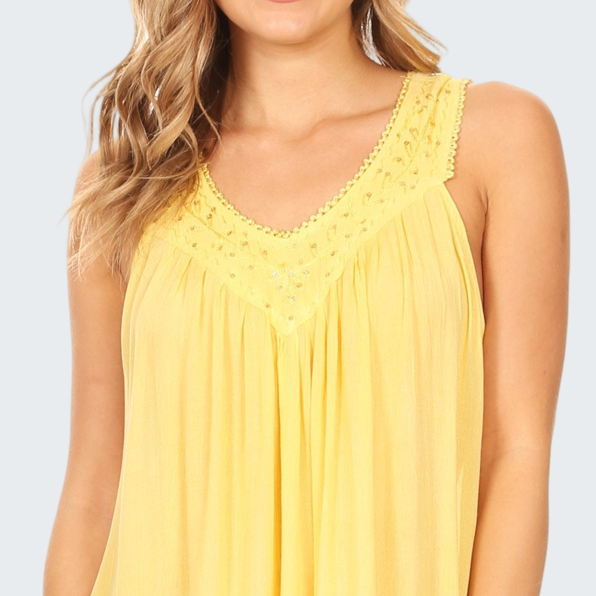 Yellow sleeveless dress worn by a person on a white background