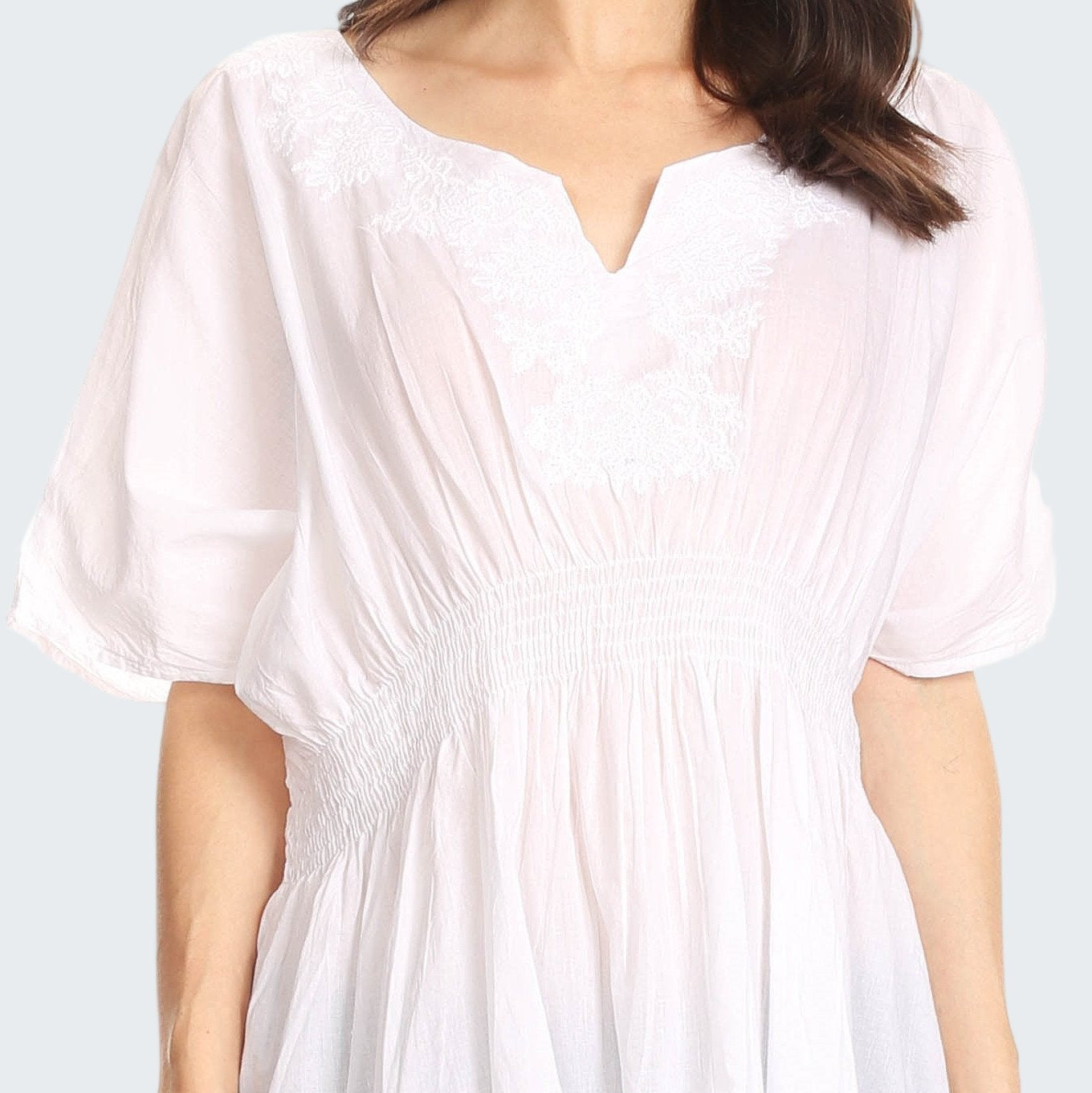 White tunic worn by a person on a plain background