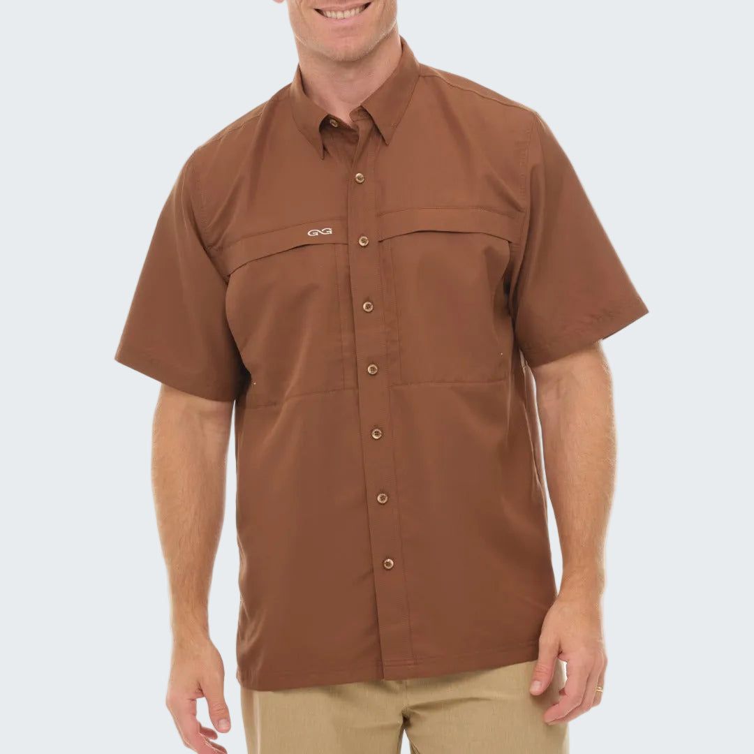Man wearing a brown short-sleeve shirt with a visible brand logo on a white background