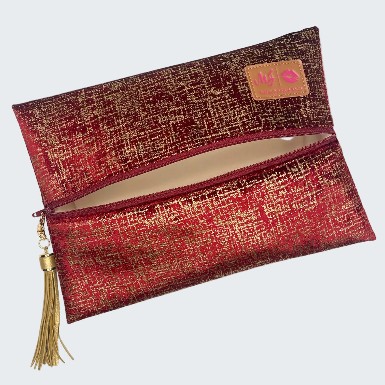 Red and gold patterned clutch bag with a tassel on a white background