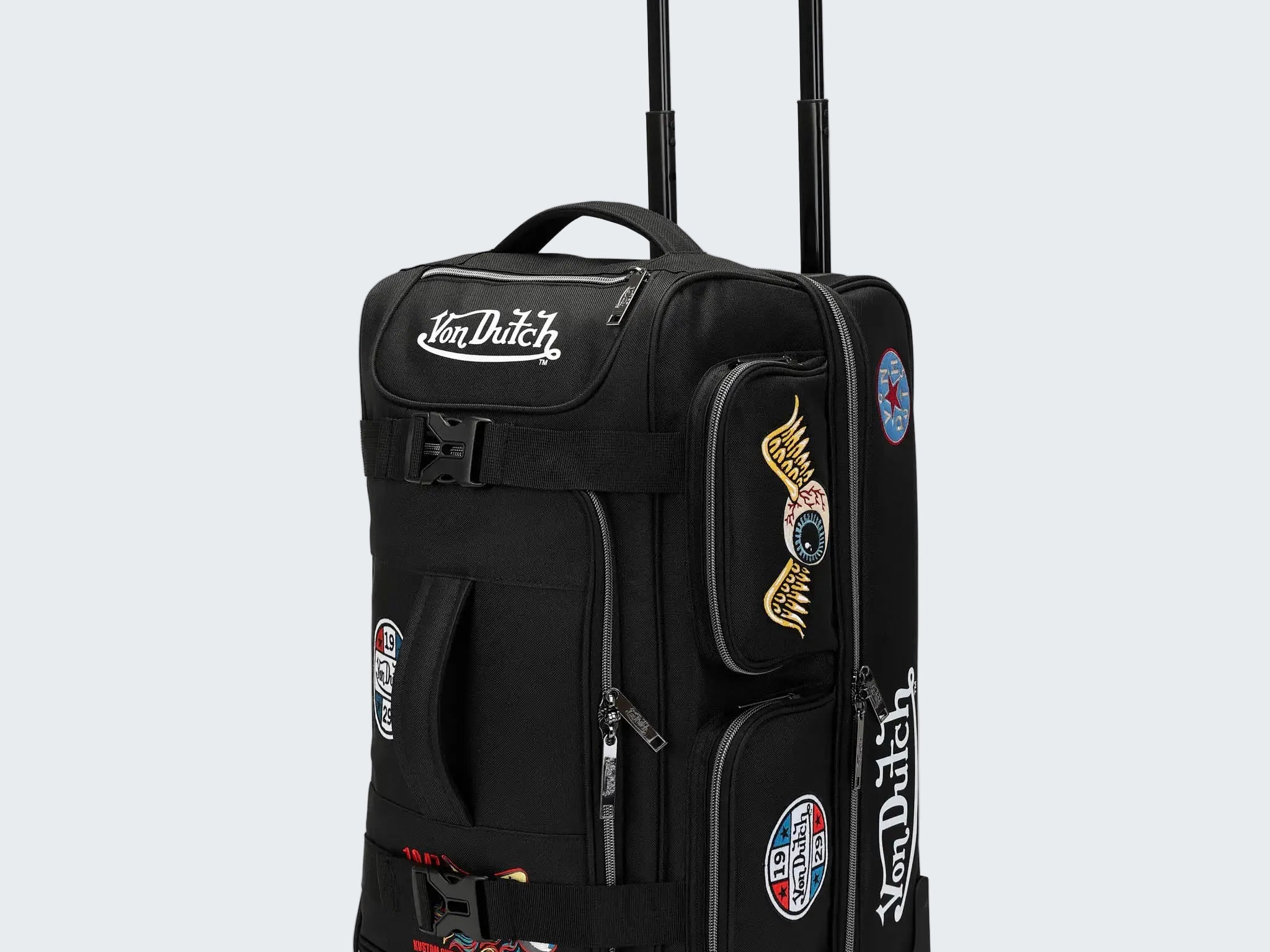 Black rolling suitcase with Von Dutch branding and patches on a white background
