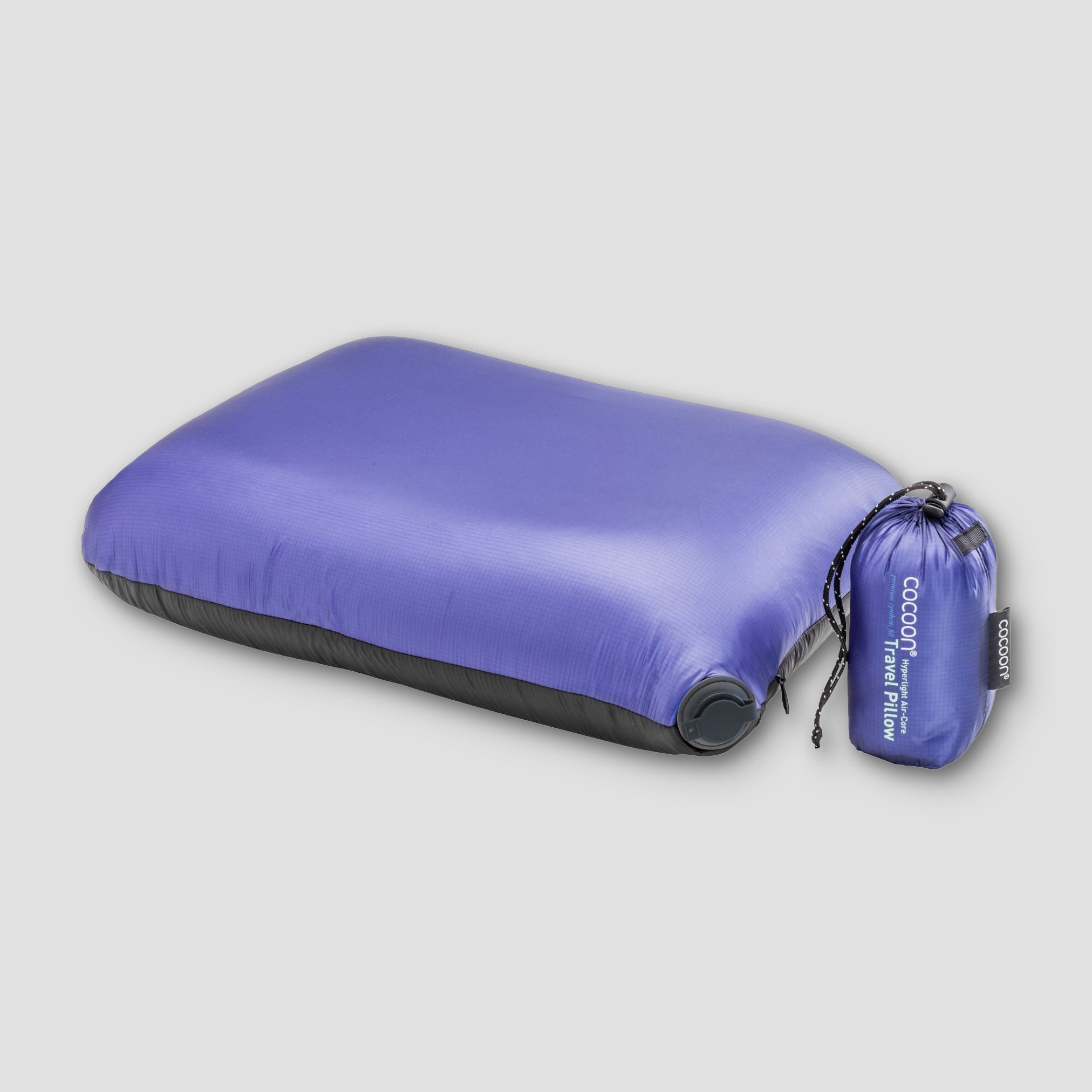 Purple inflatable travel pillow with its packaging on a light gray background