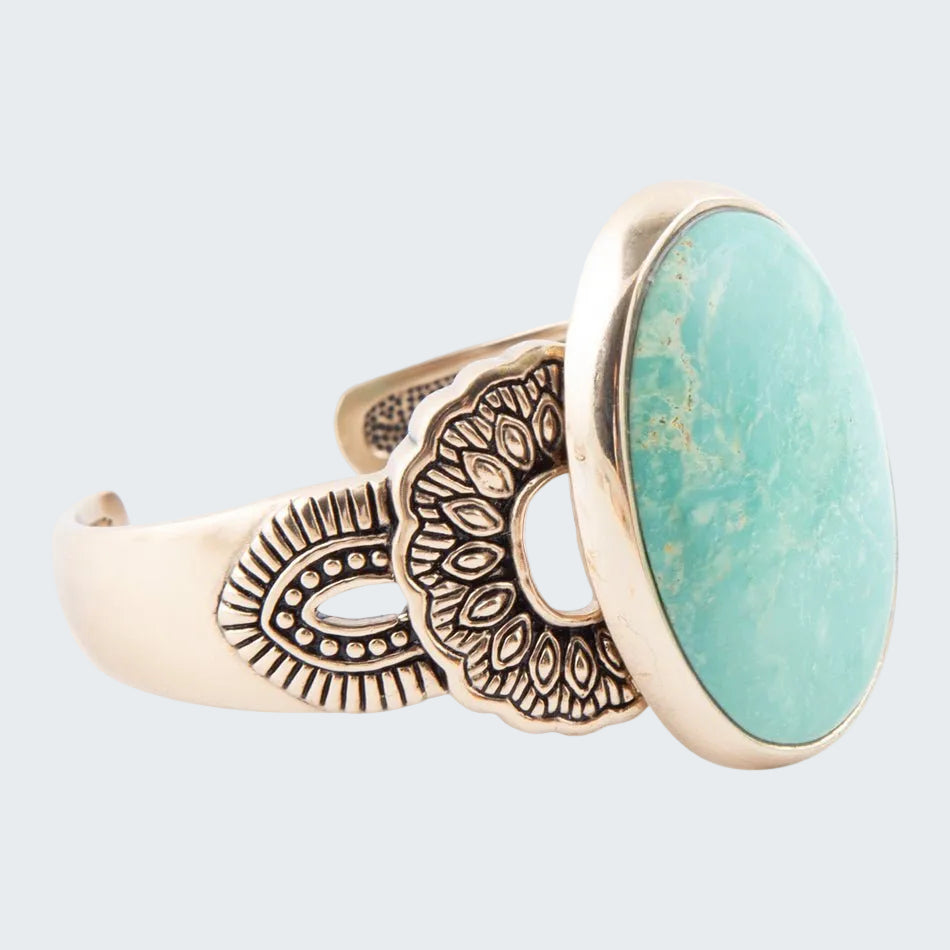 Ring with turquoise stone and bronze decorative band on a white background